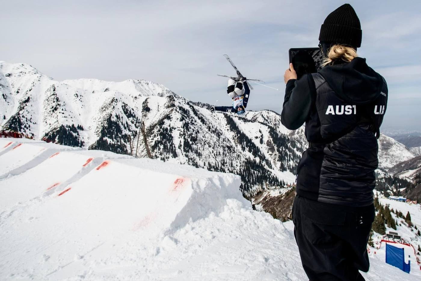 An Australian coach filming an aerial skier in competition